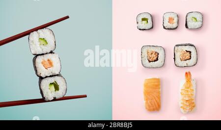 Chopsticks holding seaweed rolls filled with avocado and fish over blue and sushi over pink background Stock Photo