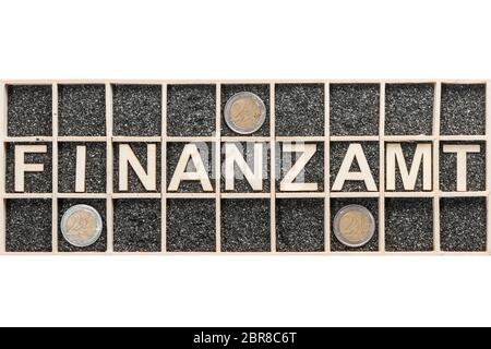 Plywood letters arranged in a collecting box with black decorative sand representing the word FINANCE and three euro coins in adjacent compartments on Stock Photo