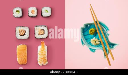 Sushi and avocado rice rolls next to fish plate holding chopsticks and green wasabi sauce over two tone pink background Stock Photo