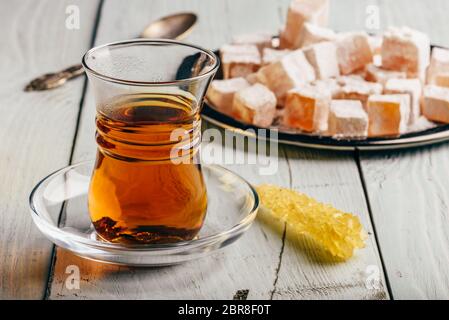 Tea in arabic glass with turkish delight Rahat Lokum over wooden surface Stock Photo
