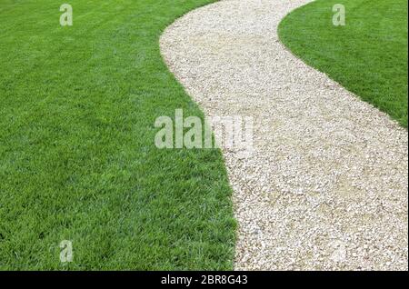 Curved garden stone path with fresh green cultivated lawn in summer Stock Photo