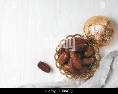 Metal plate of sweet dried dates and linen cloth on gray cement background. Dried dates with copy space. Top view or flat-lay. Stock Photo