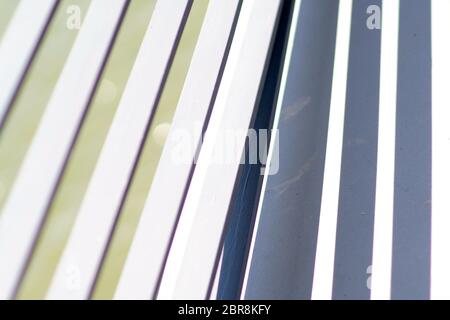 The close-up of the white-painted crossbars of a bridge railing, which casts symmetrical shadows. Stock Photo