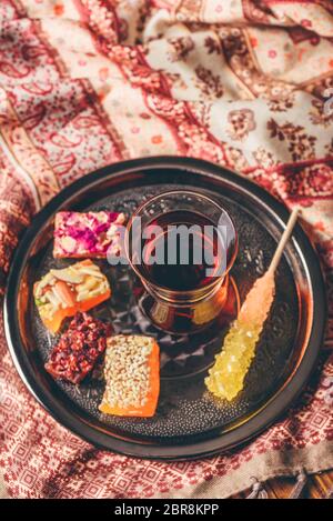Tea in armudu glass with oriental delight rahat lokum on metal tray over wooden surface and tablecloth Stock Photo