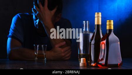 Bottles with alcoholic beverages and the figure of a drunk man Stock Photo