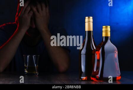 Bottles with alcoholic beverages and the figure of a drunk man Stock Photo