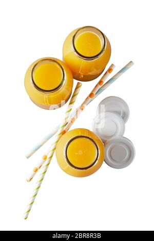 Three recyclable glass bottles of freshly squeezed orange juice rich in vitamin C viewed top down with lids and straws isolated on white Stock Photo