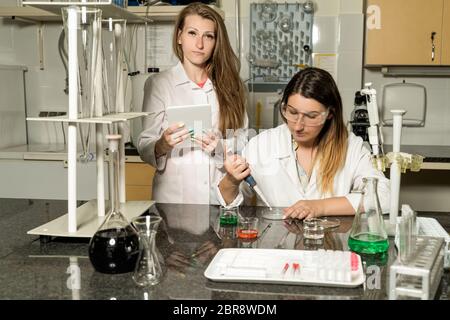 Team of two, Caucasian white, female laboratory technicians in white robes working in chemical or pharmaceutical laboratory, laboratory equipment and Stock Photo