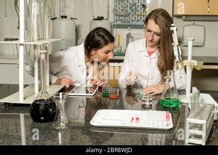 Team of two, Caucasian white, female laboratory technicians in white robes working in chemical or pharmaceutical laboratory, laboratory equipment and Stock Photo