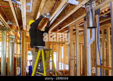 The electrician nailing to the ceiling lamp, installs the lighting lamp in the laying ceiling Stock Photo