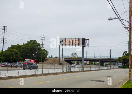 Coronavirus Covid-19 sign on the 55 freeway warning motorists your actions save lives. Travelling south on the 55 freeway Orange county , California Stock Photo