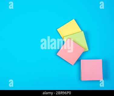 multicolored empty paper square stickers on blue background, copy space Stock Photo