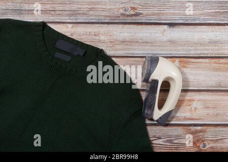 wool sweater with electric lint remover on wooden background Stock Photo