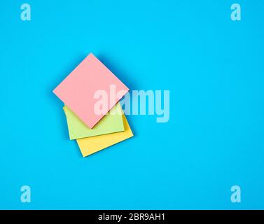 multicolored empty paper square stickers on blue background, copy space Stock Photo