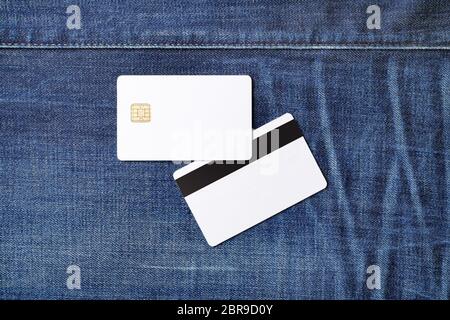 Bank white plastic chip cards on denim background. Two credit cards. Front and back view. Flat lay. Stock Photo