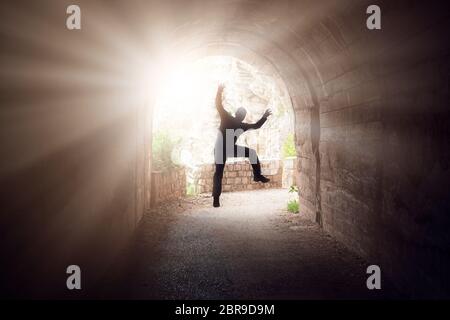 Silhouette of a man jumping in a dark tunnel on the walking path in Petrovac bay,Montenegro Stock Photo