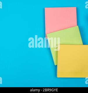multicolored empty paper square stickers on blue background, copy space Stock Photo