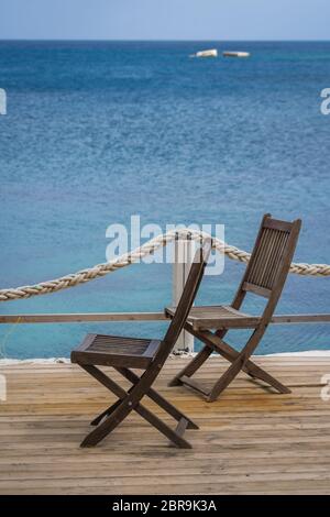 Wooden chairs on a deck platform in Agios Nikolaos beach on Zakynthos Island, Greece Stock Photo
