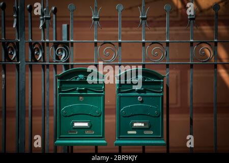 Two vintage green mail boxes on a fence. Stock Photo