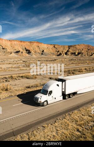 White big rig semi truck with cargo trailer on a Utah Highway Stock Photo