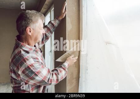 Diligent plasterer man or worker working on a window opening Stock Photo