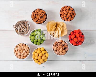 Assortment of different snack for beer, wine, party. Peanuts in coconut glaze, green vasabi, red spicy chilli, yellow cheese glaze, chips, pistachio, Stock Photo