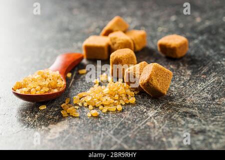 Crystalized brown sugar and sugar cubes on old kitchen table. Stock Photo