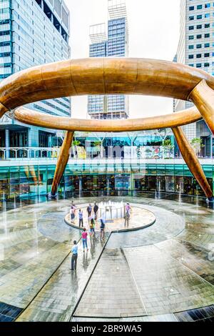 SINGAPORE - MARCH 26, 2015 : Tourists walk toward the Fountain of Wealth believed to impart luck to anyone encircling it 3 times and touching the wate Stock Photo