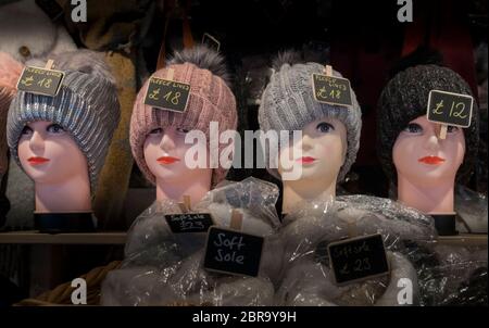 A row of female mannequin heads on a market stall wearing a knitted hat Stock Photo