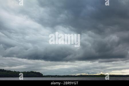 Dramatic dark stormy sky with huge heavy rain clouds before a thunderstorm. Lake Seliger, Russia. Atmospheric natural background with space for copy, Stock Photo
