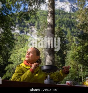 Female hiker/climber preparing supper on gas burner in a camp Stock Photo