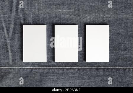 Mockup of three blank vertical business cards on gray denim background. Copy space for text. Flat lay. Stock Photo