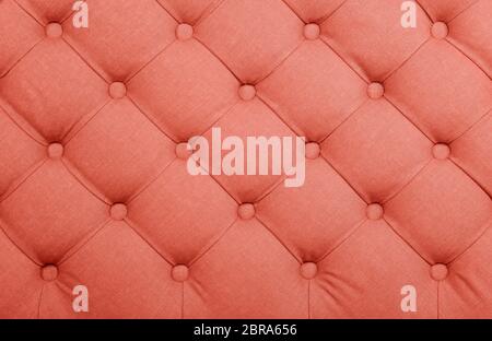 Coral toned pink capitone textile background, retro Chesterfield style checkered soft tufted fabric furniture decoration with buttons, close up Stock Photo