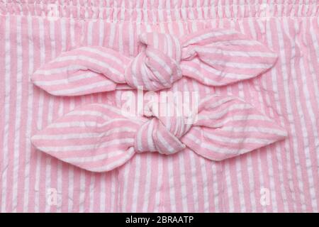 Bow on dress. Close-up details of two decoration ties at pink white striped summer dress of little girl. Macro. Stock Photo