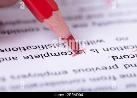 Close-up Of Red Pencil Marking Error During Spellchecking Text On Paper Document Stock Photo