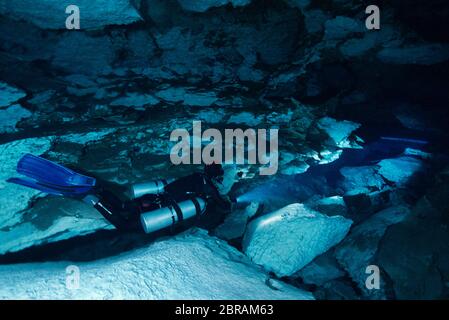 Technical sidemount diver on the cenote Calavera, know as the Temple of Doom with a strong halocline. Stock Photo