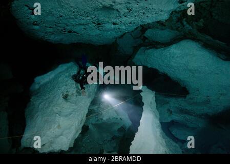 Technical sidemount diver on the cenote Calavera, know as the Temple of Doom with a strong halocline. Stock Photo