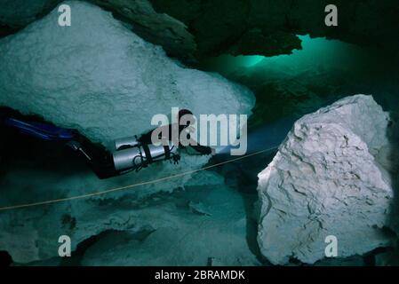 Technical sidemount diver on the cenote Calavera, know as the Temple of Doom with a strong halocline. Stock Photo