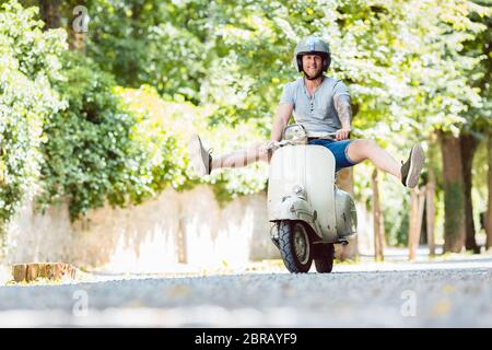 Happy carefree young man driving retro scooter Stock Photo