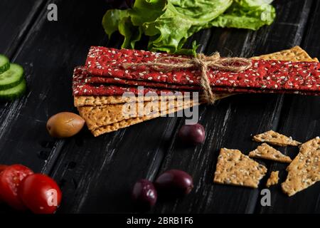 Beetroot and rye flour crackers with vegetables for making snacks on a black background. Vegetarianism and healthy eating. Stock Photo