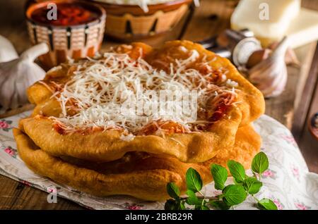 Traditional Langos are originally Hungarian fried pancakes made from yeast dough, topped with cheese, garlic and tomato ketchup. This dish is sold at Stock Photo