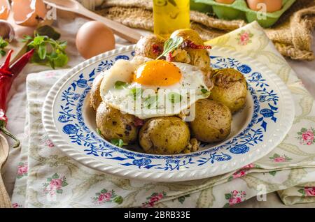 Baked potato with chili and fried egg, fresh young tomatoes and spicy chilli with herbs, great combination of flavours and spicy. Stock Photo