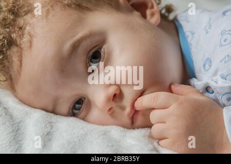 Adorable two years old kid in soft pyjamas with blue and withe colours in sunny kids room. Child's sleep concept, soft focus. Stock Photo