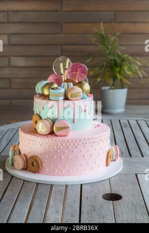 Colourful Fresh Macaroons on pastel cake in many levels on natural wooden background. Sweets concept.