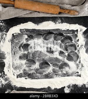 white wheat flour scattered on a black background, product is spread over the surface, kitchen background, top view Stock Photo