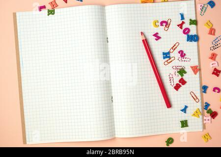 open checked notebook and red wooden pencil, back to school backdrop Stock Photo