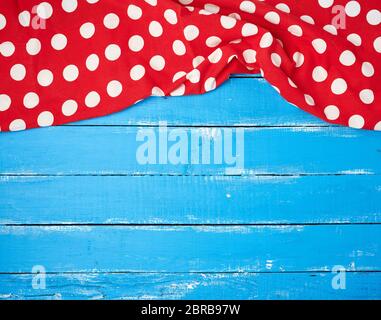 red textile towel with white circles on a blue wooden background, kitchen picnic background Stock Photo