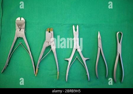 different surgical pliers lie side by side on a surgical drape Stock Photo