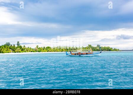 White tropical beach in Maldives with palm trees with traditional Dhoni in blue lagoon Stock Photo