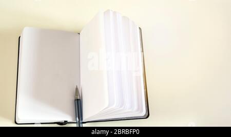 A ballpoint pen in the middle of an open notebook. Unwritten blank pages. Stock Photo